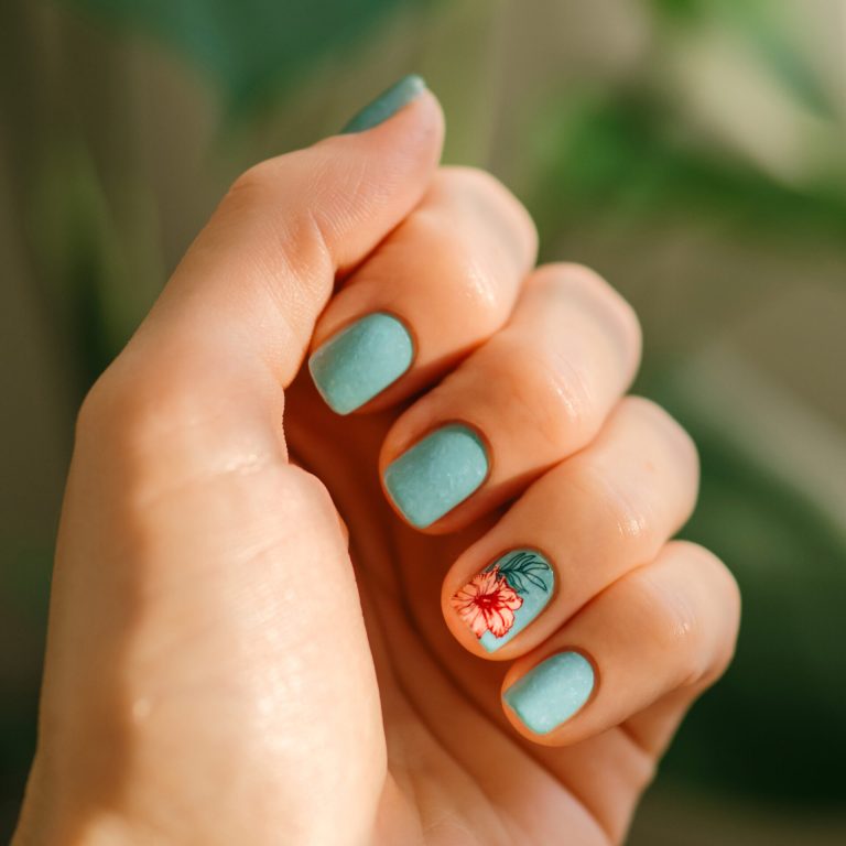 Aesthetic visual of fingernail with short nail with blue teal manicure with reverse stamping summer tropical flower. Nail closeup with stylish pink flower in reverse stamping nail art design manicure